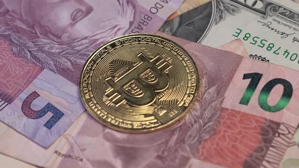 Bitcoin Crypto Currency Coin on Brazilian Reals and American Dollars Banknotes