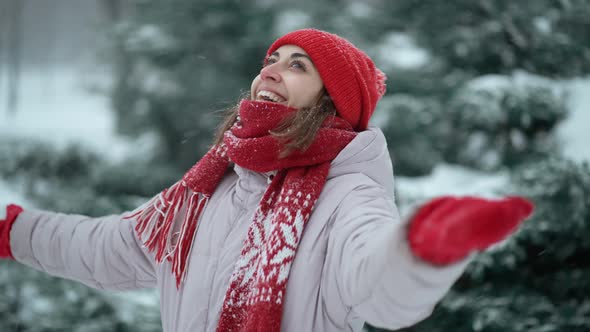 Slow Motion Beautiful Smiling Woman in Knitted Red Beanie and Scarf Standing in Park at Winter