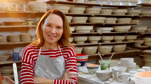 Female potter standing with arms crossed in pottery workshop 4k