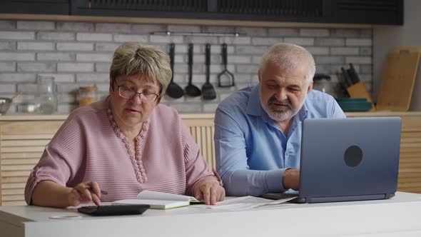 Elderly Spouses are Spending Weekend at Home Woman is Calculating Utility Bills and Her Husband is