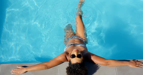 Overhead of young mixed-race woman relaxing in swimming pool 4k