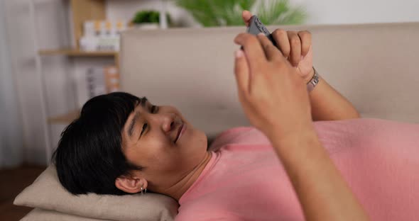 Man user watching movie on smartphone relax on sofa at home