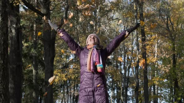 Happy Woman Throwing Dry Autumn Leaves Above Her