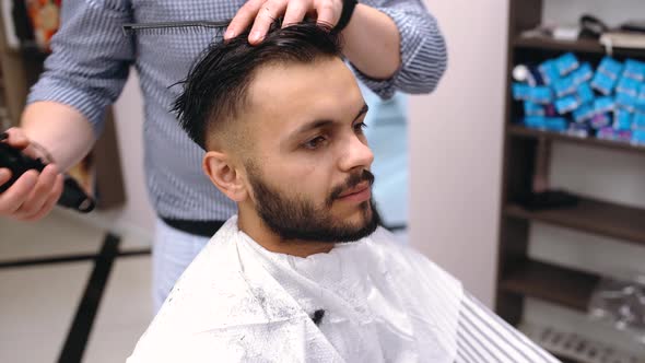 A Young Man Impressed By the Work of a Barber Smiles. He Is Very Satisfied.