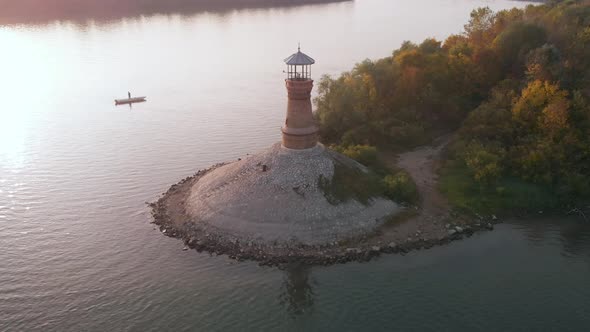 Orbiting footage around the old stone lighthouse on the Danube river with sunset in the background a