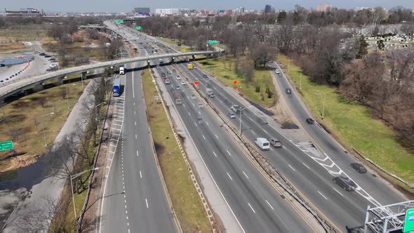 An aerial time-lapse over a busy highway on a sunny day between a lake and a graveyard in Queens, Ne