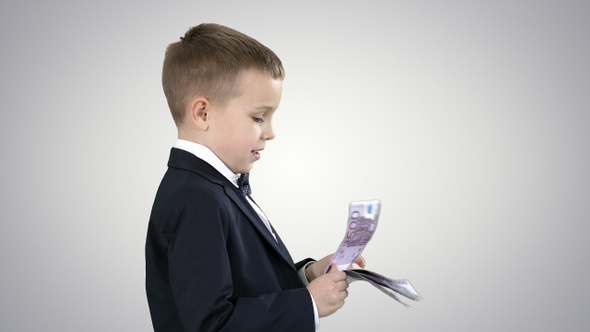 Little boy in black suit counts money on gradient background.