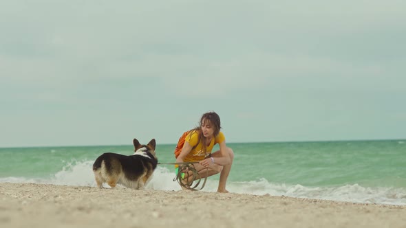 Attractive Young Woman Spending Time Together with Her Pet Cute Corgi Dog Outdoors at Sandy Sea