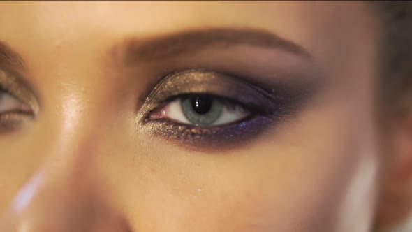 Closeup View of Woman's Eyes with Beautiful Golden Makeup Opening in Slowmotion