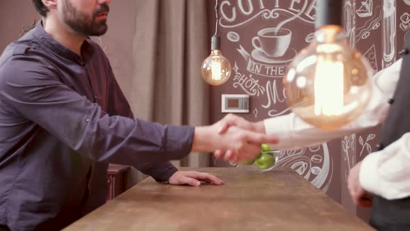 Young Man Greeting the Bartender and Sits at a Bar Counter