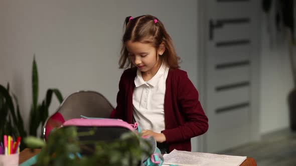 Schoolgirl put books and notes into backpack at home