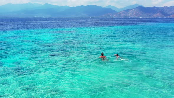 Two young female teenagers swimming in the crystal clear aqua water in perfect tourist holiday desti