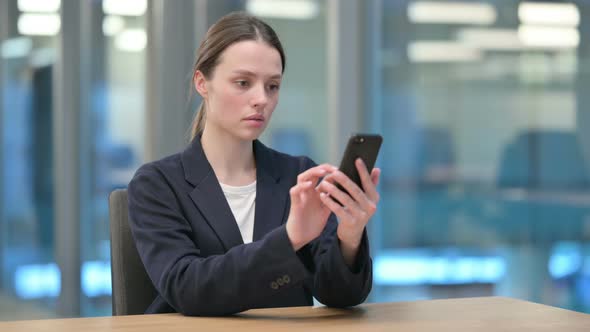 Attractive Young Businesswoman using Smartphone at Work