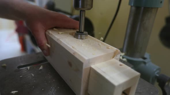 Drilling out a tenon slot in a wood beam on a drill press in slow motion as wood chips are displaced