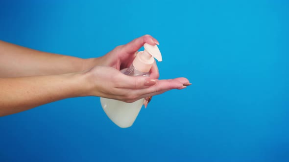 Washing Female Hands on Blue Background Pushing Dispenser and Using Liquid Soap or Foam