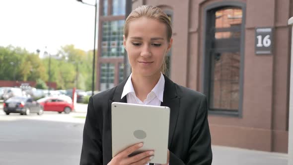 Woman Walking Ouside Office and Browsing on Tablet