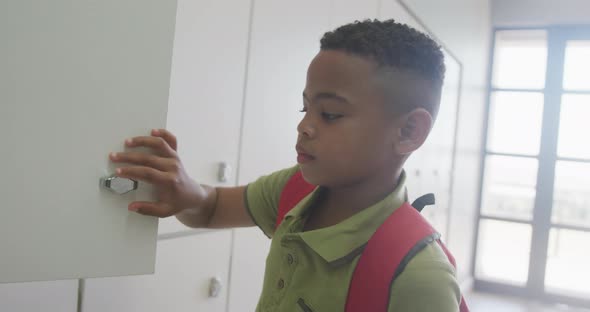 Video of african american boy closing locker and smiling at school