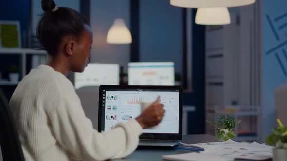 Black Manager Checking Business Statistics and Financial Reports on Laptop