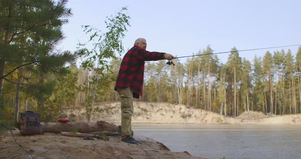 Spin Fishing of Middle-aged Man in Forest Lake, Man Is Casting Rod and Rotating Reel During Angling