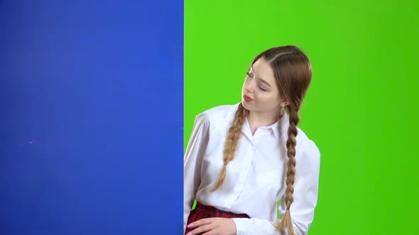 Schoolgirl Looks Out From Behind a Blue Board and Shows Ok. Green Screen