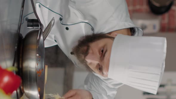 Vertical Video Male Chef Pouring Shredded Cheese on Cooked Food in Frying Pan