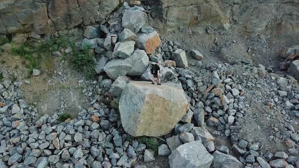 Top view of the young tourist going down from the big stone outdoors.