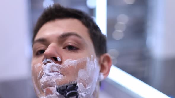 Handsome Man Shaving His Beard in Bathroom By Mechanical Razor