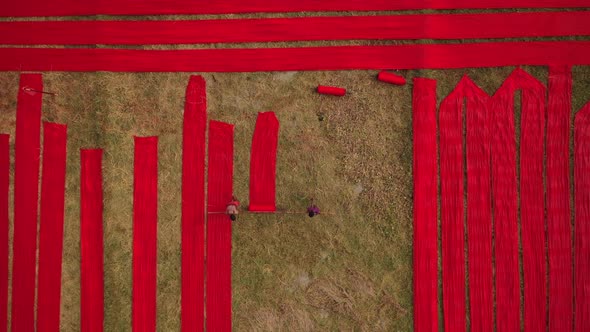 Aerial view of a man walking along red long textile stripes, Bangladesh.