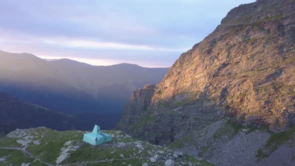 Wide aerial view from drone circling over base camp on small plateau with rugged terrain and steep m