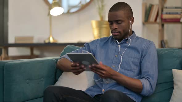 Young African Man Meditating Using Tablet on Sofa