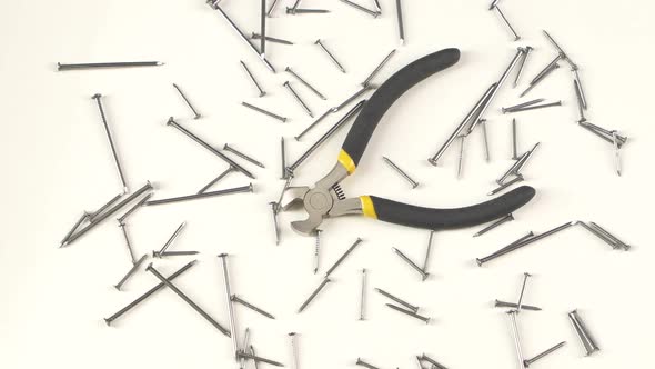 Wire Cutters with Yellow, Gray Handle on White Among Nails, Rotation, From Above