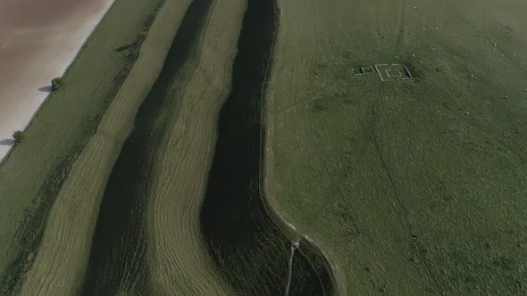 Aerial panning up from a topdown view over Maiden Castle, to reveal an amazing panoramic scene show