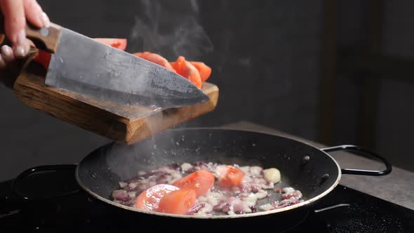 Adding Sloced Tomato Into Pan with Frying Onion Oil Splashing