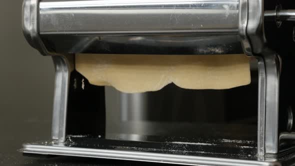 Close-up of flattened dough in  pasta machine 4K 2160p 30fps UltraHD footage - Italian lasagna sheet