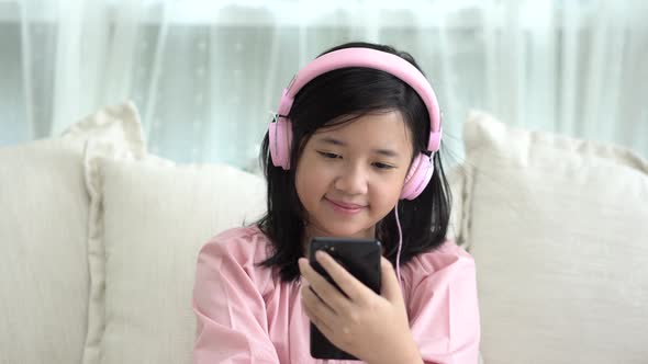 Beautiful Asian Girl Listening To Music  Sitting On A Sofa In The Living Room At Home 