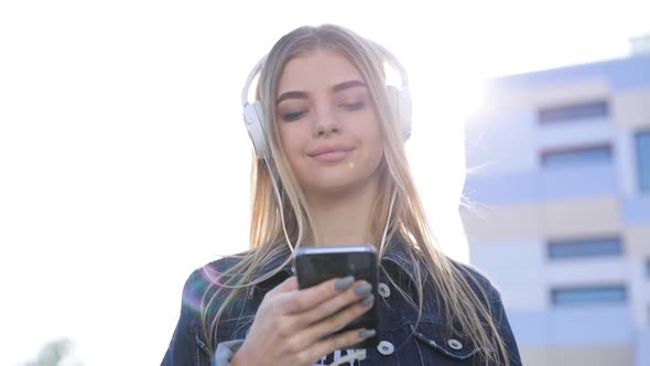 Beautiful Woman In Headphones Listening Music On Phone Outdoors