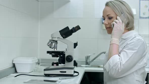 Female Lab Worker with White Coat Using Mobile Phone at His Workplace in the Laboratory