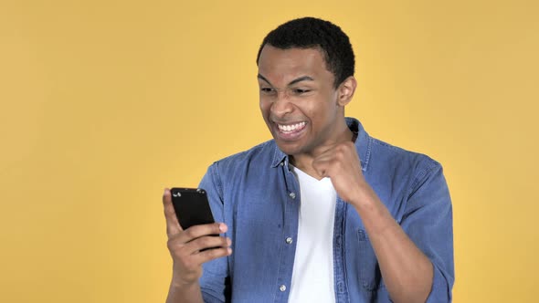 Young African Man Excited for Success While Using Smartphone