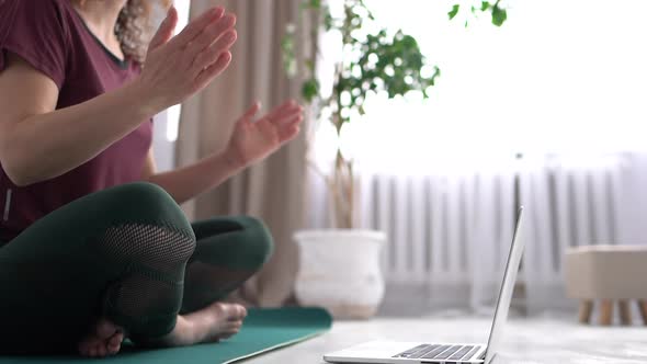 Adult Woman Working Out at Home Doing Yoga Exercise on Green Mat Sitting in Lotus Position and