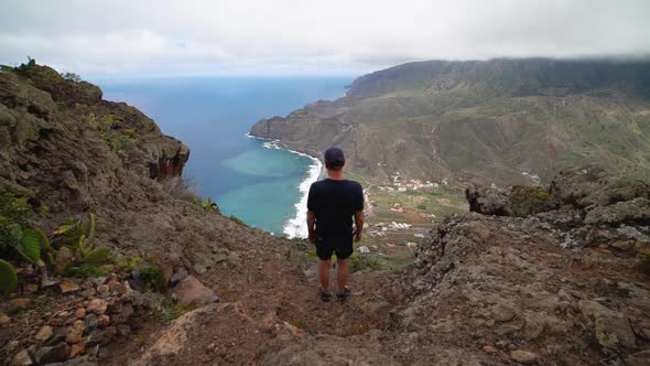 Man On Mountain Looking At Coastline And Sea