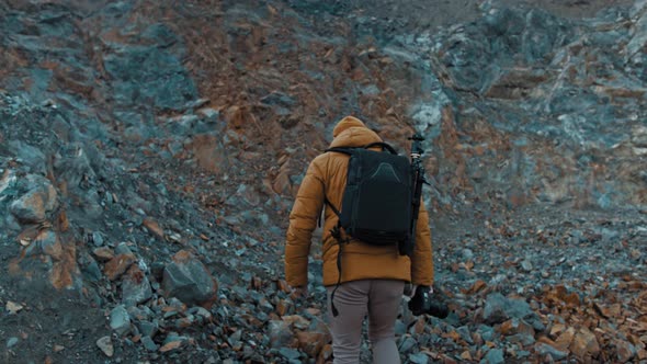 Bearded Man in a Hat with a Backpack Comes Down From the Mountains