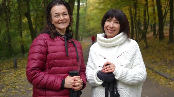 Medium Shot Portrait of Two Happy Mature Women Looking at Camera Smiling Standing on Alley in Autumn