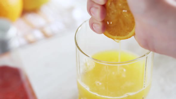 Close Up Of Homemade Orange Juice Making. A Woman's Hand Presses Juice Into A Glass Glass