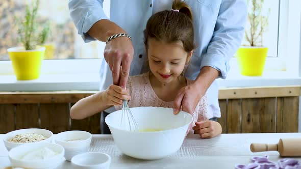 Father and daughter preparing dough together in kitchen