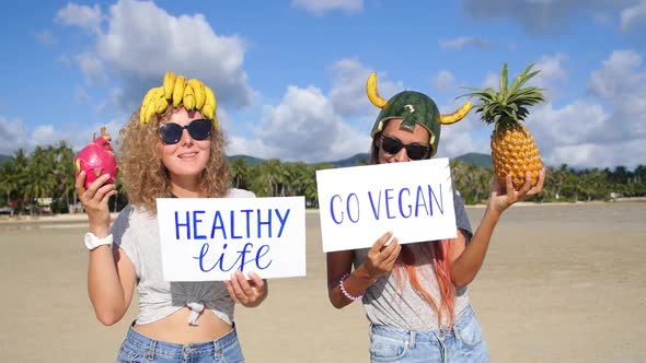 Healthy Vegan Lifestyle: Funny Cheerful Women Friends With Fruits on Beach