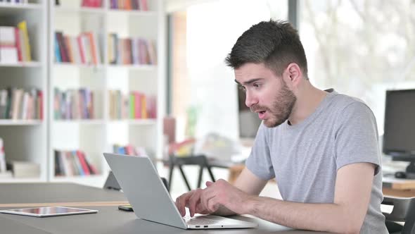 Successful Young Man Celebrating on Laptop in Office