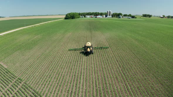 Aerial, tractor spraying pesticide on fresh crops in rural agricultural farm field. Series