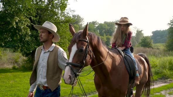 A Young Cowboy is Leading a Horse on Which His Daughter is Sitting