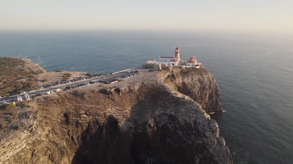 Aerial of red and white striped lighthouse sitting on the edge of the cliffs in Sagres, Portugal