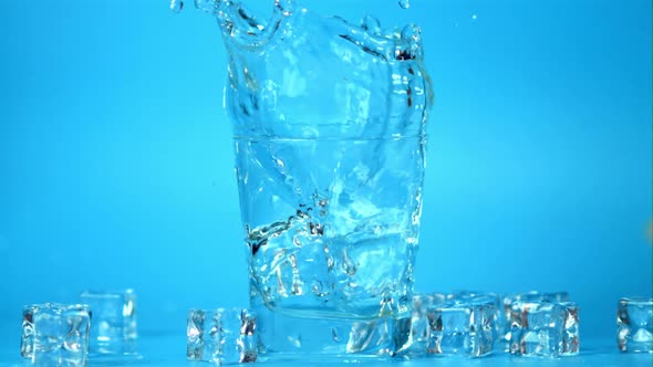 Super Slow Motion Ice Falls with Splashes in a Glass of Water